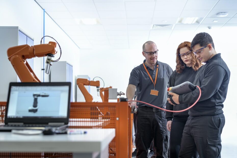 Robotics apprentices using test industrial robots in robotics facility